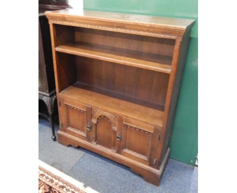 An oak cupboard bookcase, with two open shelves, over panelled cupboard doors, raised on bracket feet, 84cm x 26cm x 103cm.