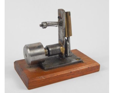 A small piston stationary engine, in chrome with brass mounts on wooden base, 16cm wide.