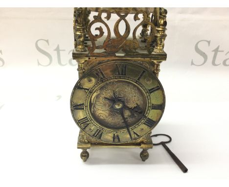A brass lantern clock. Winds and runs. Approximately 21cm tall.