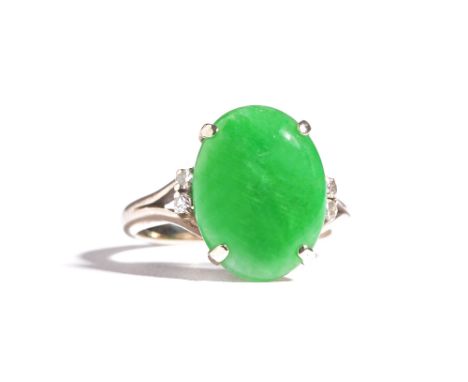 A jade and diamond ring, claw set with the oval jade between circular cut diamond set two stone split shoulders, ring size K.