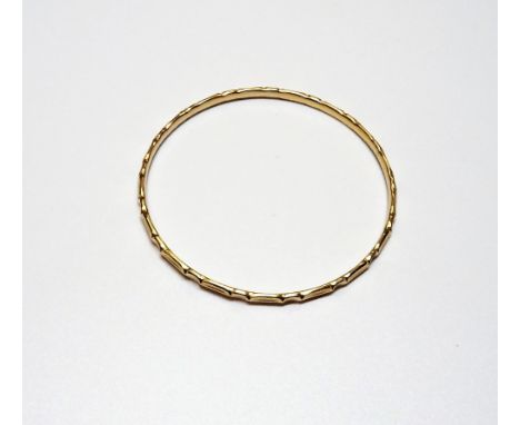 A gold circular bangle, with faceted decoration, weight 9.3 gms.