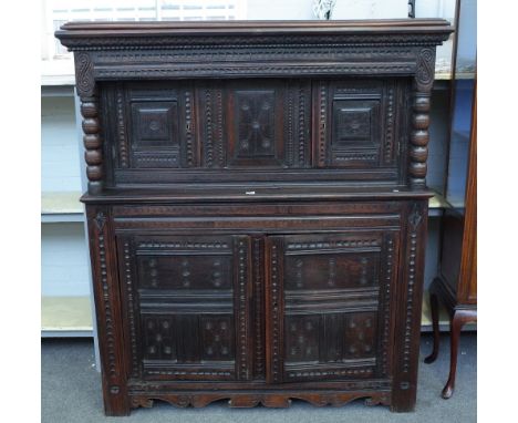 A 17th century and later oak court cupboard with raised double panel doors, flanked by bobbin turned columns, over a pair of 