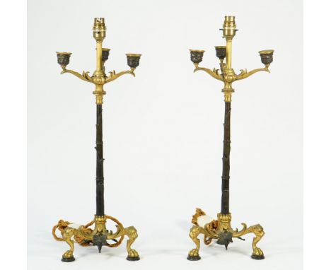 A pair of Regency style gilt and patinated three branch candelabra, converted to table lamps, each leaf cast column issuing t