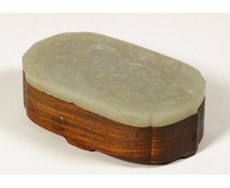 A Chinese hardwood box with jade cover, late 19th/20th century, of shaped oblong form, the thinly carved jade of pale celadon