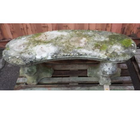 A 20th century reconstituted stone concave garden bench with carved lion mask supports, 120cm wide x 40cm high. 