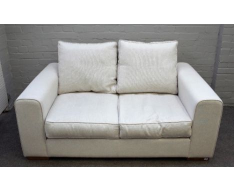 Heals; a Moretta small seat sofa upholstered in cream fabric on block feet, 163cm wide x 75cm high. 