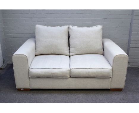 Heals; a Moretta small seat sofa upholstered in cream fabric on block feet, 163cm wide x 75cm high. 