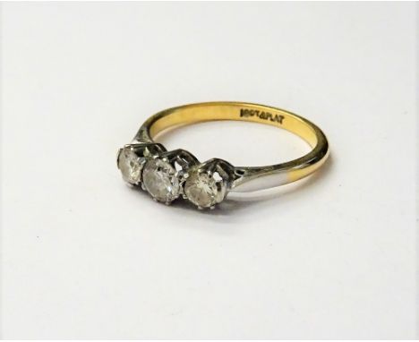 A gold and platinum, diamond set three stone ring, claw set with a row of circular cut diamonds, detailed 18 CT &amp; PLAT, r