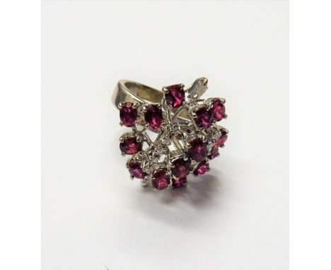 A ruby and diamond ring, in a pierced abstract design, mounted with mostly oval cut rubies, two rows of small circular cut di