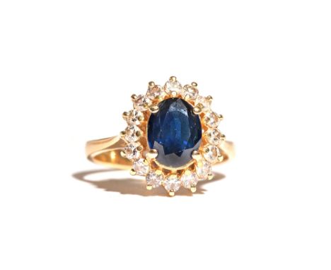 A gold, sapphire and diamond oval cluster ring, claw set with the oval cut sapphire in a surround of circular cut diamonds, d