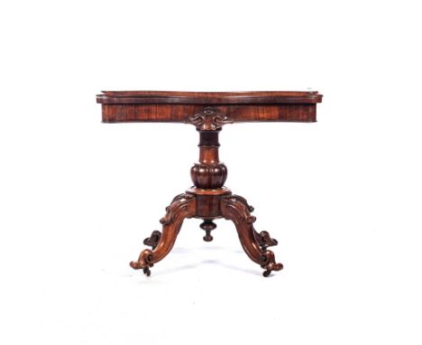 The hinged serpentine top concealing a baize playing surface above a plain frieze, centred by a foliate-carved and scrolling 
