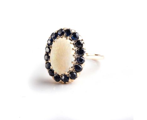 The claw-set cabochon opal surrounded by sixteen pavé-set old-cut sapphires, in 18ct gold, size L