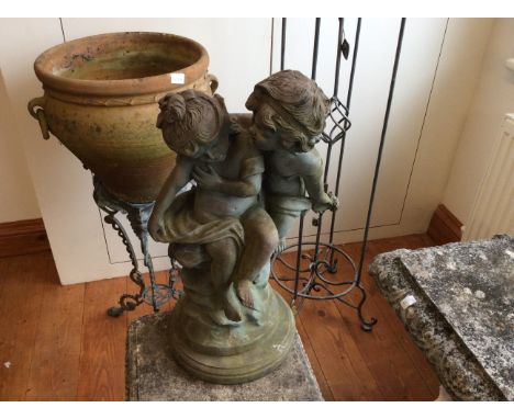 A terracotta planter on metal base, cast iron plant stand, with a plastic garden ornament of children. 