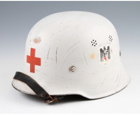 A DRK German Red Cross helmet in white with red cross to front with swastika emblem to side, has leather liner.