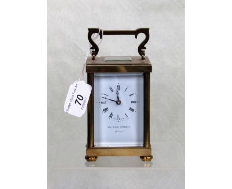 A gilt brass carriage clock on four bun supports, the dial bearing Roman numerals, signed Matthew Norman, London, having Swis