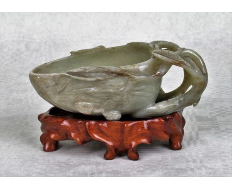 A Chinese carved jade libation cup, the handle formed as stylized branches and leaves, with relief berry decoration throughou