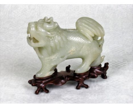 A Chinese pale celadon jade study of a lion, the body having extensive decoration, 12cm wide on bespoke hardwood stand.