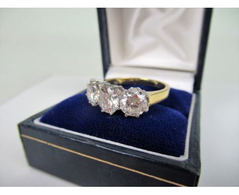 A three stone half-hoop diamond ring, the slightly graduated brilliant cut diamonds in raised claw mounts to plain shank.   C