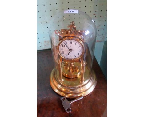 An early 20th century brass anniversary clock under fitted glass dome, the enamel dial bearing Arabic numerals, 30cm.