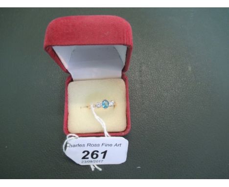 An 18ct and yellow white gold three stone half-hoop ring, having central oval cut aquamarine stone flanked by two circular cu