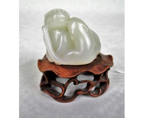 A Chinese pale celadon jade carved figure group of a lioness and cub, 4.5cm wide, together with carved hardwood display stand