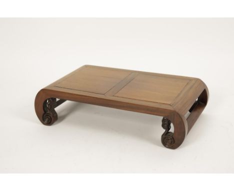 A CHINESE HARDWOOD KANG-FORM STAND with two panel top, on foliate-carved scroll ends, late Qing-Republic, 5" high x 21" wide