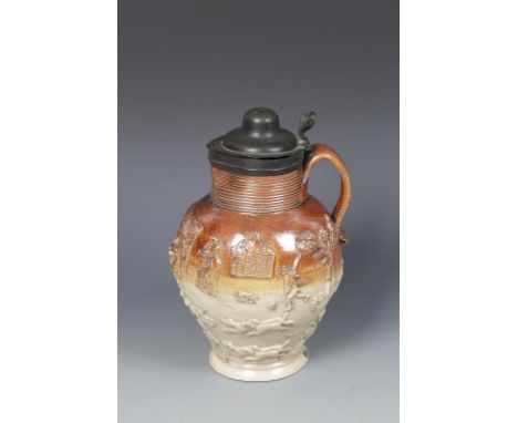 A SALT GLAZED STONEWARE JUG with decoration in high relief of figures, hunting scene, buildings and trees, the rim with reede