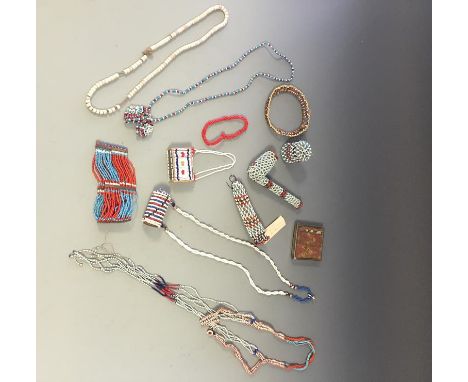 A COLLECTION OF AFRICAN AND SIMILAR BEADS including a bracelet worked with rows of red and blue beads, a bead covered pipe an
