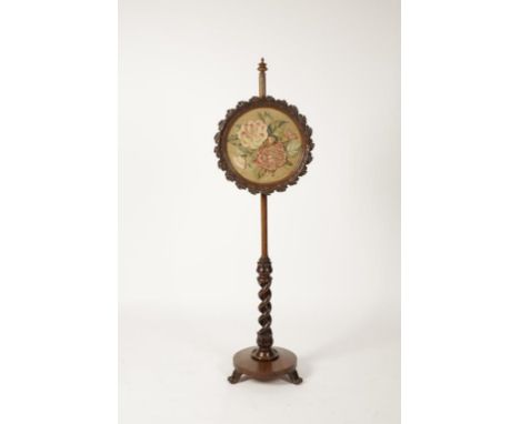 AN EARLY VICTORIAN ROSEWOOD POLE SCREEN, the circular screen with raised foliate needlework within a leaf-carved surround, on