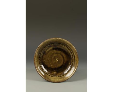 RICHARD BATTERHAM (b.1936) A STONEWARE DISH with an incised tooth border and green glaze, 9" dia. See illustration