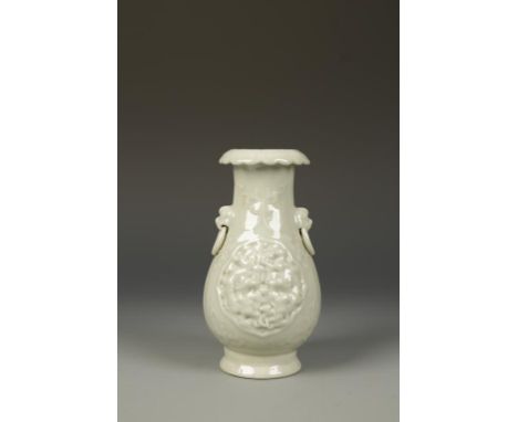 A CHINESE CELADON VASE, with a flared foliate neck and mask/ring-handles, the body with relief ogee panels of dragons among c