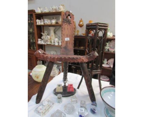 A carved wood birthing stool and a bamboo stand