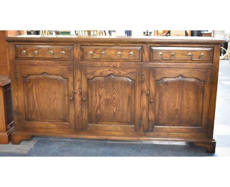 An Oak Sideboard with Three Panelled Cupboard Doors, Surmounted by Three Drawers on Bracket Feet, 167cms Wide