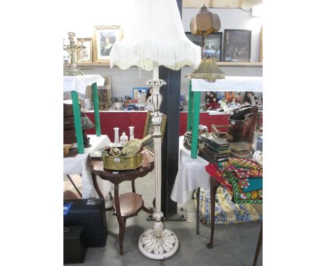 A white and gold painted wooden standard lamp with shade