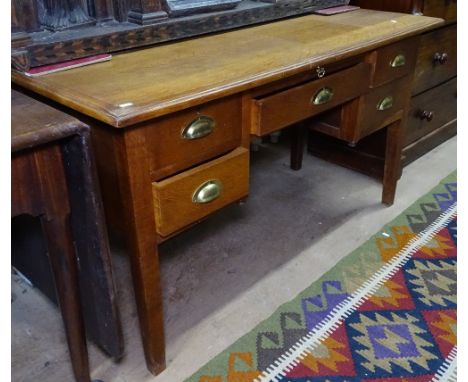 A 1920s light oak kneehole writing desk, with 5 short drawers, W133cm, H73cm, D61cm 