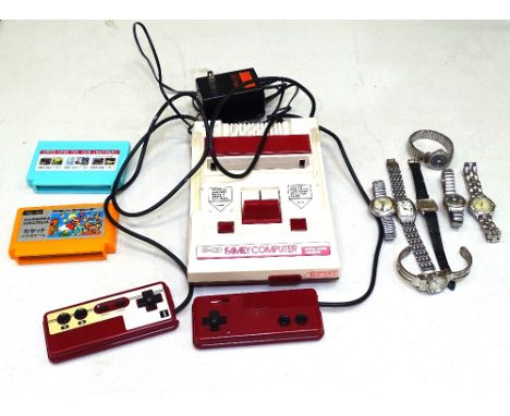A vintage Nintendo games console with 2 controllers and cartridges and a collection of watches 