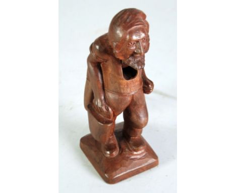 TWENTIETH CENTURY CARVED PROBABLY SWISS SOFTWOOD NUT CRACKER IN THE FORM OF A STANDING MAN, the pivoting handle forming the o