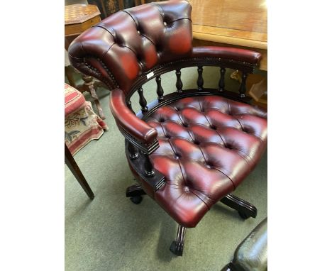 A RED leather and button backed swivel arm chair, with wooden galleried back and five splayed reeded legs to plastic castors 