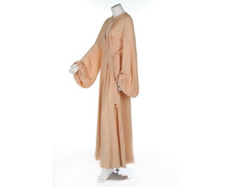 An Ossie Clark 'Come Fly With Me' peach moss crepe evening gown, circa 1975, labelled and size 12, wrap around style, the ver