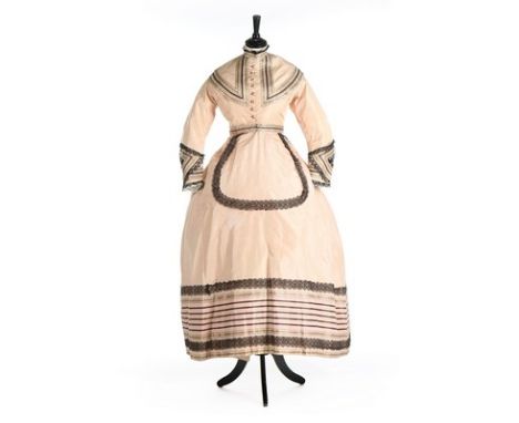 A striped pink taffeta afternoon dress, circa 1865, adorned with woven ribbons and black bobbin lace, comprising bodice, skir