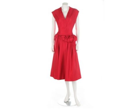 A red silk couture dress, circa 1955, with padded, twisted band to the low waistline, zip and button closure to the back, bus