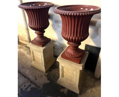 Pair of cast iron fluted campana shaped pedestal vases standing on ceramic square section panel design pedestals. Overall 110