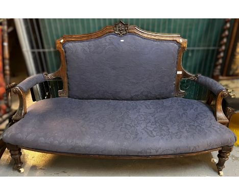Late Victorian walnut show frame sofa, with arched back, open arms, bow fronted stuff over seat on turned legs with ceramic c