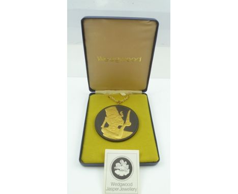 A WEDGWOOD BLACK JASPER PENDANT gilded in the Egyptian taste with a royal profile portrait wearing cobra crown, 7cm diameter,