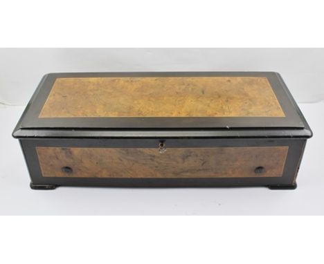 A 19TH CENTURY MUSICAL BOX having walnut veneered and ebonised case, playing six airs including Suppe, Faust and Verdi, the l