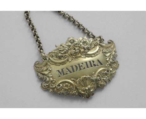 A GEORGE IV SILVERGILT, ESCUTCHEON-SHAPED WINE LABEL with a raised border of flowers, shells and scrolls, pierced "MADEIRA", 