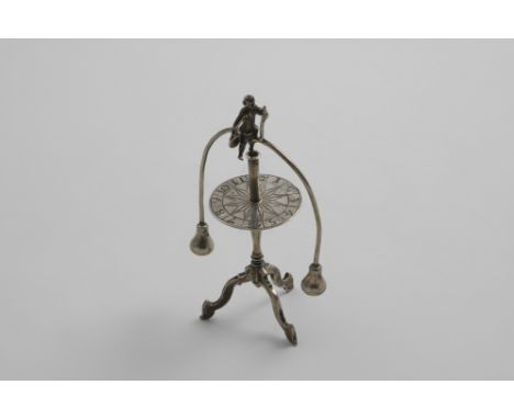 A DUTCH NOVELTY OR TOY GAMING PIECE in the form of a figure on an arched, weighted wire balancing on a tripod table, struck w