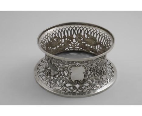 AN EDWARDIAN IRISH DISH RING of conventional spool form pierced around the sides and decorated with repousse-work garlands of