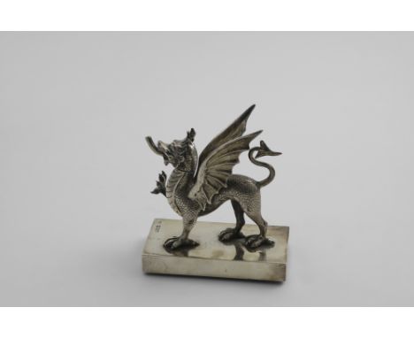 AN EDWARDIAN NOVELTY TABLE LIGHTER cast in the form of a gryphon with a pull-off head on a rectangular base with four small c