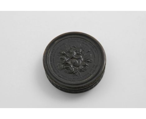 AN EARLY 19TH CENTURY PRESSED HORN CIRCULAR SNUFF BOX dark in colour, with a putto, roses, a bee and lines of verse in relief